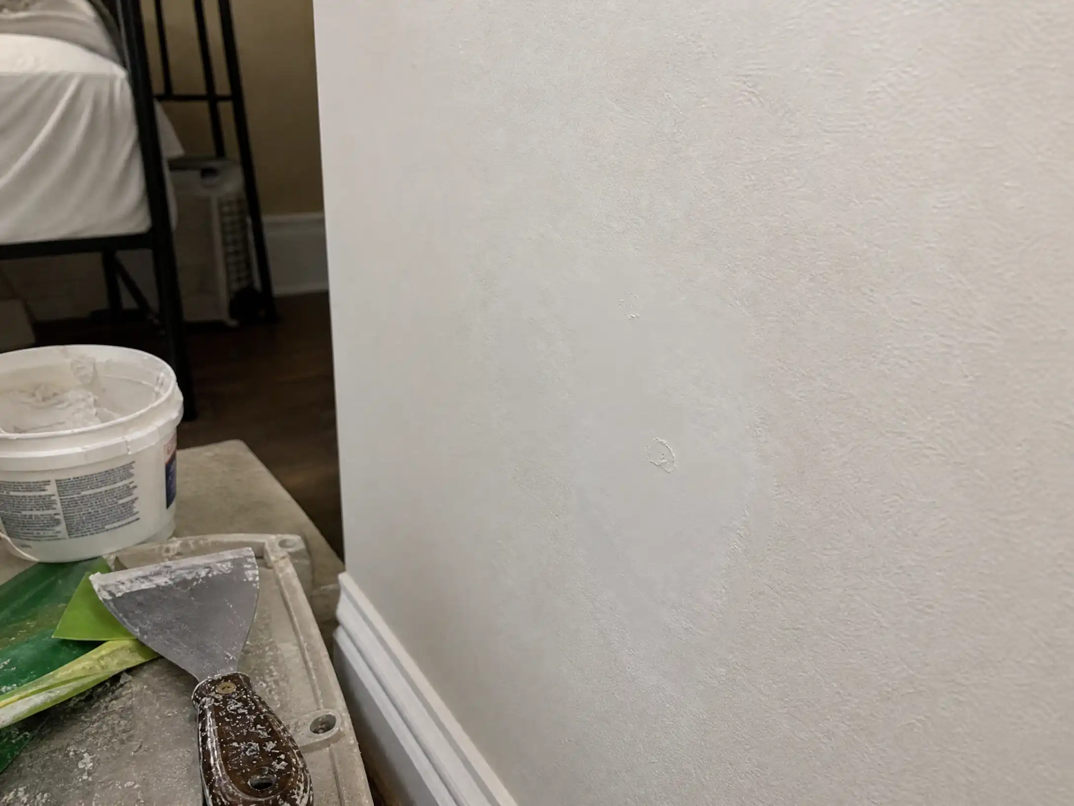 A nail pop spot filled with joint compound and sanded smooth, ready for primer and paint