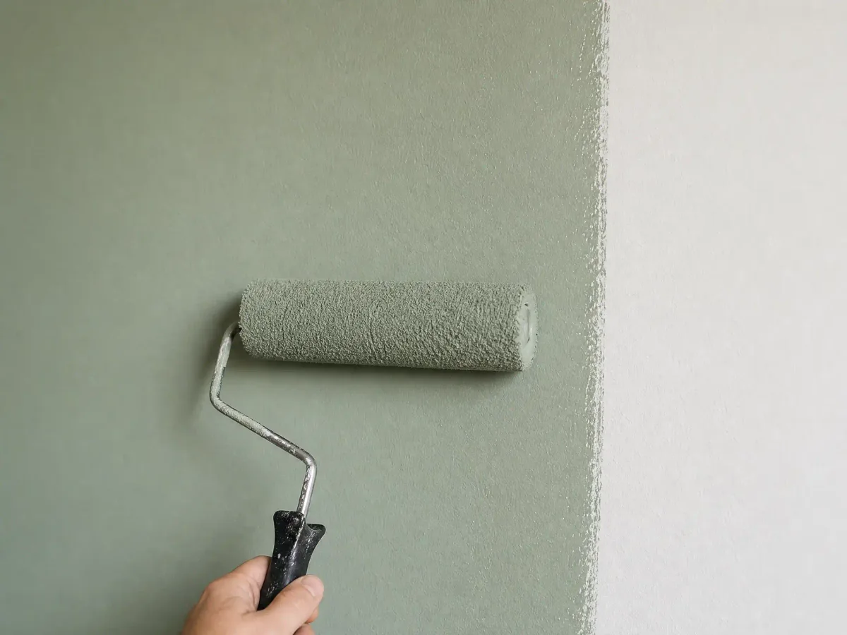 A sage wall mid-roll showing a wet, even overlap with no lap marks