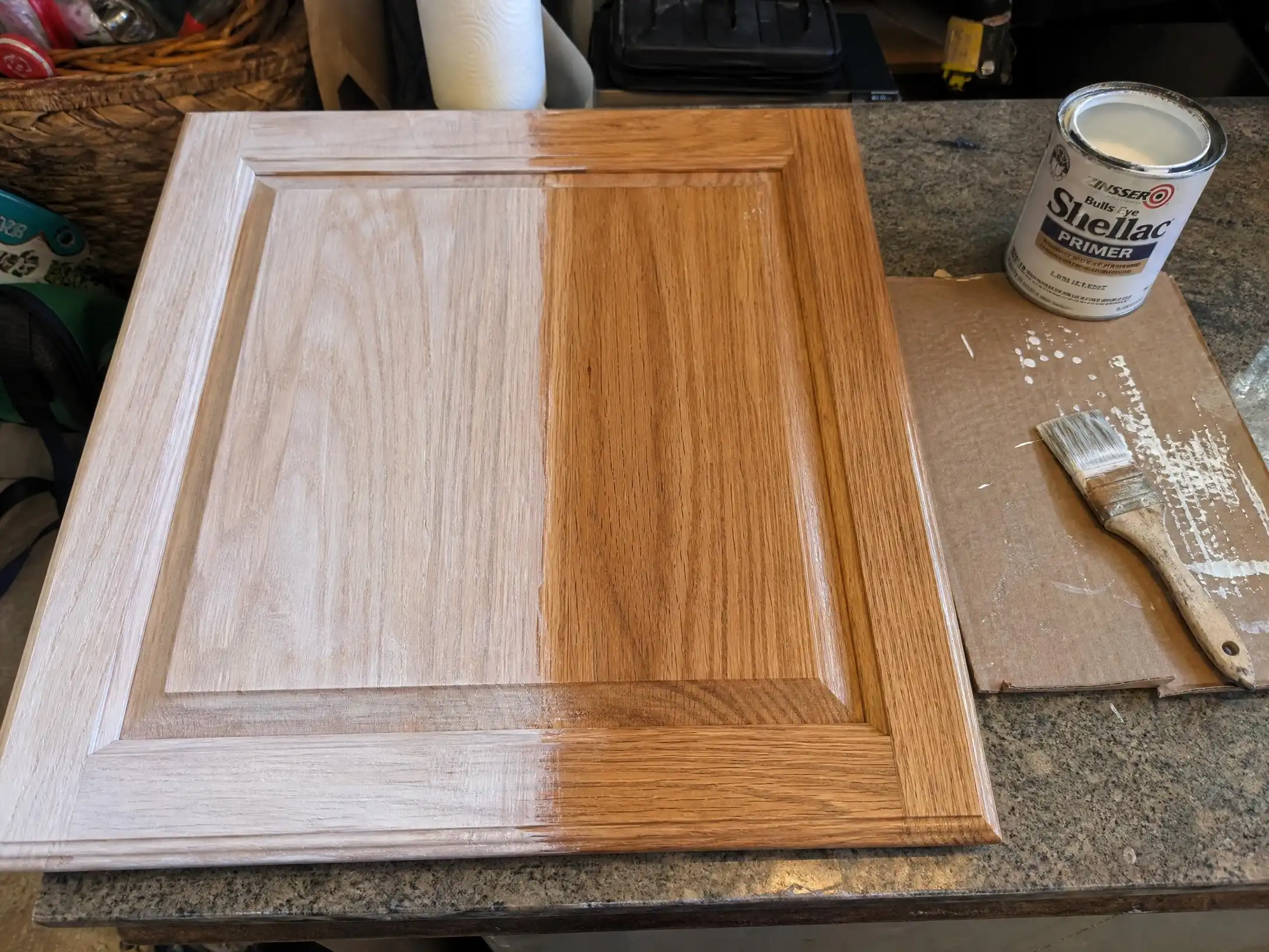 Shellac-based primer being brushed onto a flat oak cabinet door panel to seal the grain and block tannin bleed-through